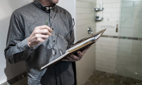 Mann som holder briller og penn i hånden og ser i en mappe